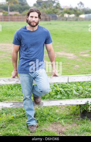 Man leaning on wooden fence Stock Photo