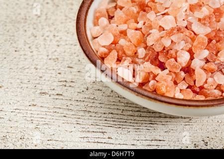 Himalayan salt coarse crystals in a ceramic bowl on a rough white painted barn wood Stock Photo