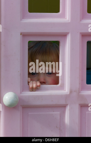 A toddler girl age one peeking out of a playhouse Stock Photo