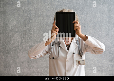 Female doctor holding digital tablet in front of face Stock Photo