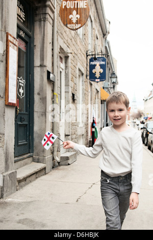 boy walking on Rue Saint Paul in old Montreal waving a flag of Montreal Stock Photo