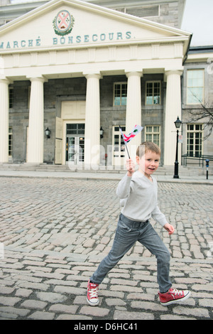 Boy waving a flag of Montreal in front of Marché Bonsecours Market in Old Montreal Stock Photo