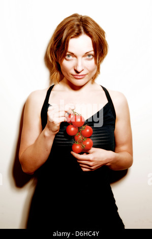 A young woman holding a bunch of vine tomatoes Stock Photo