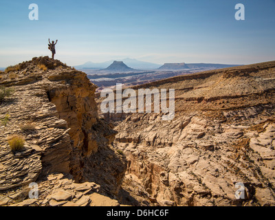 Hiker cheering on rocky hilltop