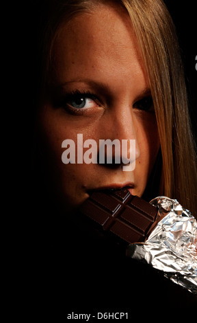 A young Blonde Woman eating a Chocolate bar Stock Photo