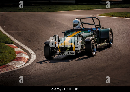 Front and side view of a green and yellow Caterham Seven car racing at Cadwell park race track. Stock Photo