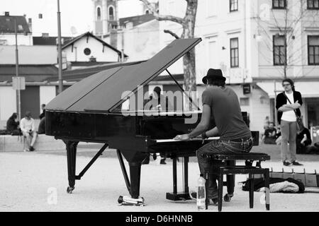 Davide Martello, AKA Klavierkunst (piano art), plays his black grand piano in the park of Kongresni Trg, Ljubljana, Slovenia. Davide is currently travelling the world on a mission to play his grand piano in every capital city in the world. On Tuesday April 16th he played here in Ljubljana. Check out more about Davide on his website: http://www.klavierkunst.com/ Stock Photo