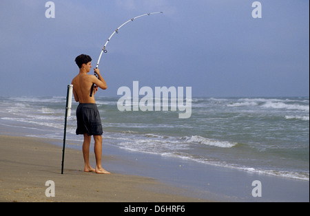 Surf fisherman reeling in a fish on North Padre Island Texas Stock Photo