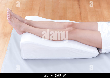 A woman's legs lay down on a pillow for relaxing and preventing varicose vein Stock Photo