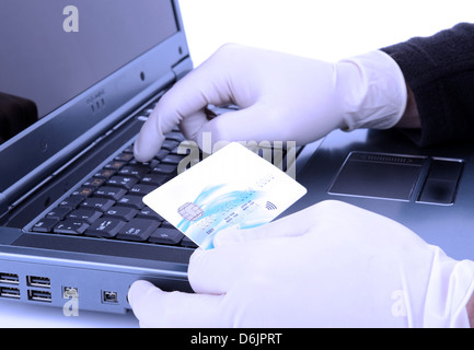 thief with protective glove online stealing with stolen credit card with a blue negativity filter Stock Photo