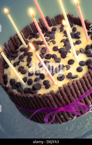 Birthday celebration cake decorated to sticks of chocolate with 8 lit candles. Stock Photo