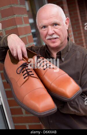 Shoemaker Georg Wessels presents a pair of oversized men's shoes in front of his shop in Vreden, Germany, 15 April 2013. Wessels manufactures shoes for people with large shoe sizes all around the world. Photo: Friso Gentsch Stock Photo