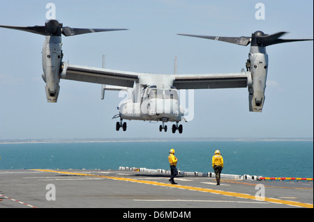 US Navy flight operations sailors direct a MV-22 Osprey aircraft to land on the deck of the multipurpose amphibious assault ship USS Bataan April 10, 2013 in the Atlantic Ocean. Stock Photo