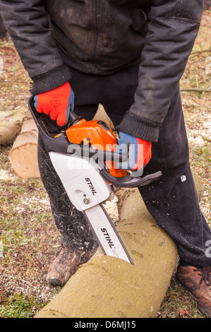 A man cutting logs with a chainsaw showing movement in the Uk Stock Photo