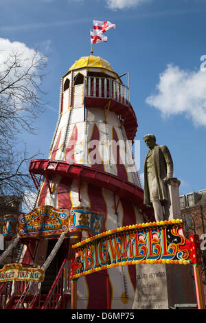Old traditional wooden Helter-Skelter, a Childrens's fairground  spiral slide at Manchester Weekend.  Statue of Oliver Heywood surrounded by amusement rides at the St George's weekend celebrations, a family event held in Albert Square and Piccadilly, an extension of the annual St George Parade and a venture to help celebrate England's Patron Saint' Stock Photo