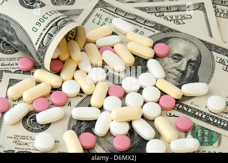 Pills of different colors on money background. Stock Photo