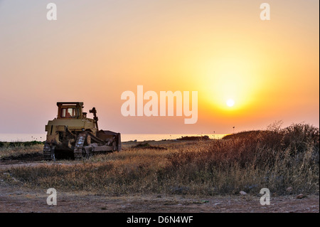 Bulldozer on the beach at sunset Stock Photo