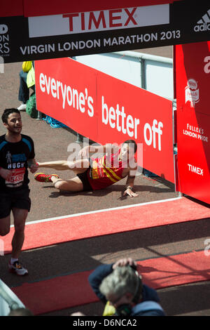 A runner collapses and crawls over the finish line of the 2013 Virgin London Marathon in The Mall. Stock Photo