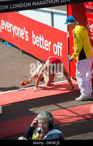 A runner collapses and crawls over the finish line of the 2013 Virgin London Marathon in The Mall. Stock Photo