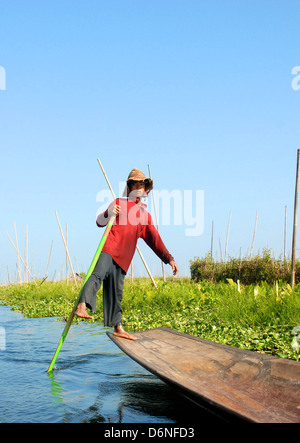 a man standing on flats boat platform uses pole to push through