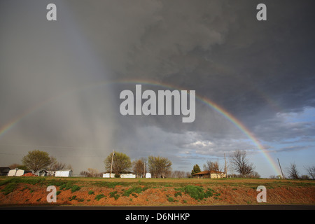 A double rainbow in a storm cloud over homes in rural Oklahoma. Stock Photo