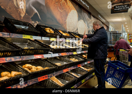 A man choosing freshly baked bread and other items from the bakery display at Lidls supermarket, Aberystwyth UK Stock Photo