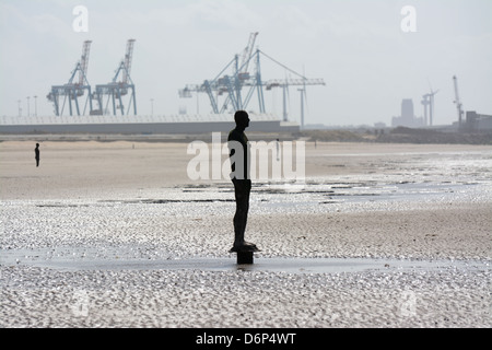 Antony Gormley's Another Place statues on the beach at Crosby with Liverpool docks in the background Stock Photo