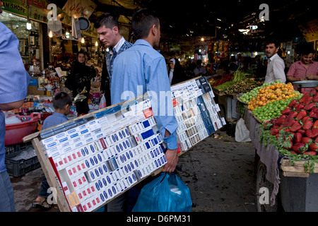 A man carrying a wooden box of cigarettes enters the busy Old Market in Erbil city centre, Iraq to sell his goods. Stock Photo