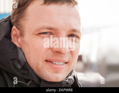 Close up outdoor portrait of young smiling man in cold season Stock Photo