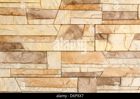 Fragment of a wall of the house covered with a light brown ceramic tile, imitating a natural stone. Stock Photo