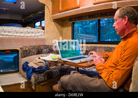 Professional photographer H. Mark Weidman editing digital photographs on a laptop computer inside a camper Denali National Park Stock Photo