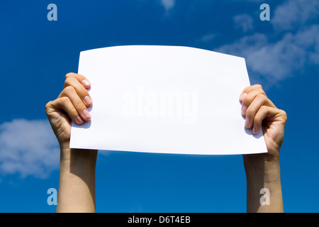 blank page in hands on blue sky background Stock Photo