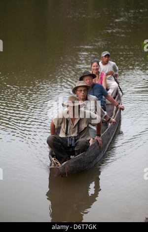 Eco-tourists with local Amerindian Guide paddling in a dugout canoe around an ox-bow lake deviating from the River Rewa. Guyana. Stock Photo