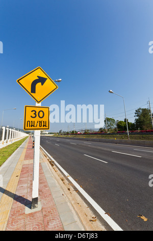 Road Sign warns Drivers to Limit Speed Ahead Dangerous Curve. Stock Photo