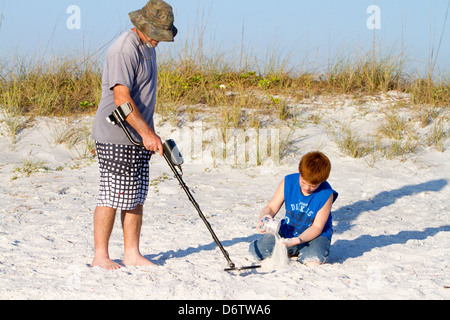 Father and son using a metal detector at the beach on the gulf coast of Florida, USA. Stock Photo