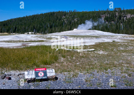 Warning signs keep tourists from wandering on the ground surrounding Old Faithful Geyser at Yellowstone National Park. Stock Photo