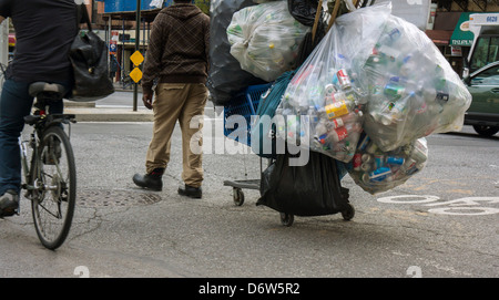 A deposit bottle collector in the bike lane in the Chelsea neighborhood of New York Stock Photo