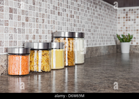 Food ingredients in glass jars on a kitchen counter top. Stock Photo