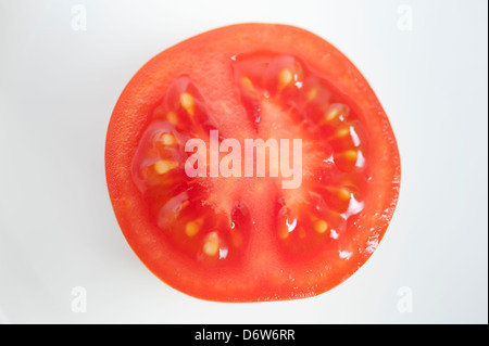 A tomato sliced in half on a white plain background Stock Photo