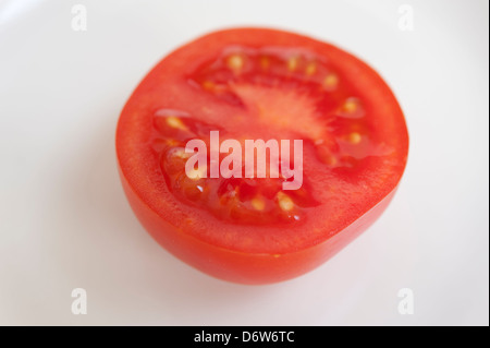 A tomato sliced in half on a white plain background Stock Photo