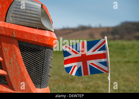 A union jack British flag on the front of a small red tractor lawnmower lawn mower Stock Photo