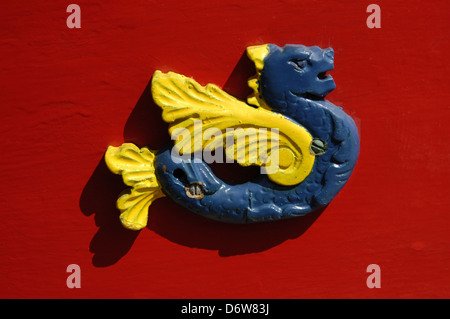 An ornamental ceramic figure in shape of a winged seahorse and vibrant painting decorates a Luzzu traditional fishing boat  from the Maltese islands Stock Photo