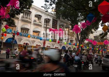 Horizontal cityscape of a busy street in Hanoi with lots of mopeds driving along during rush hour. Stock Photo