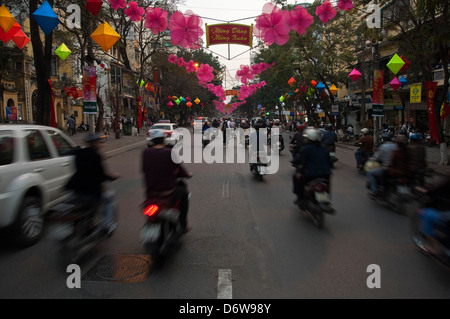 Horizontal cityscape of Hàng Bài street in Hanoi with lots of mopeds driving along during rush hour. Stock Photo