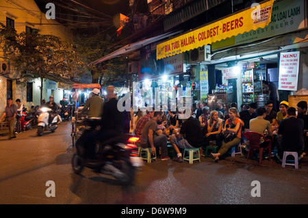 Horizontal wide angle of lots of tourists and locals drinking beer on the street in the Old Quarter in Hanoi at night. Stock Photo