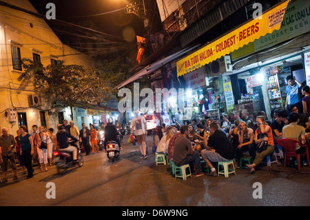 Horizontal wide angle of lots of tourists and locals drinking beer on the street in the Old Quarter in Hanoi at night. Stock Photo