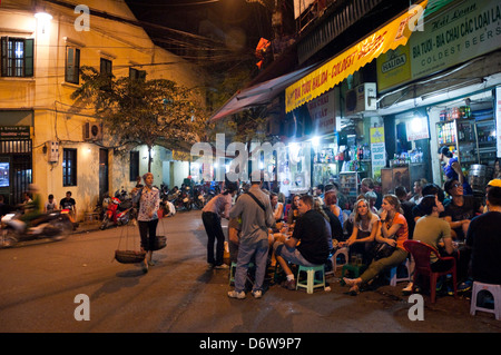 Horizontal wide angle of lots of tourists and locals drinking beer on the street in the Old Quarter in Hanoi at night. Stock Photo