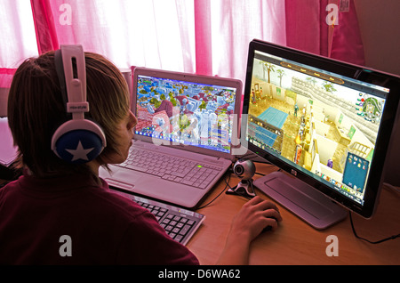 A teenage boy playing computer games on two screens Stock Photo