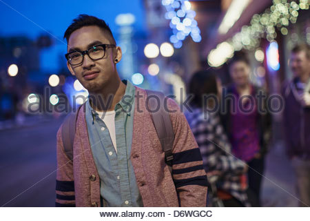 Portrait of young man smiling with friends in the background at dusk