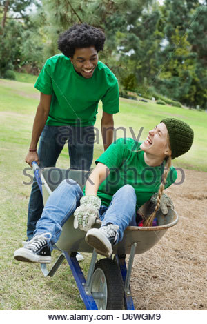 Young man pushing woman in wheelbarrow at park